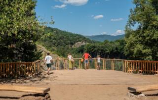 Familie, die vom Aussichtspunkt der Windkraftanlage in Jaujac aus die Landschaft betrachtet - ©sourcesetvolcans